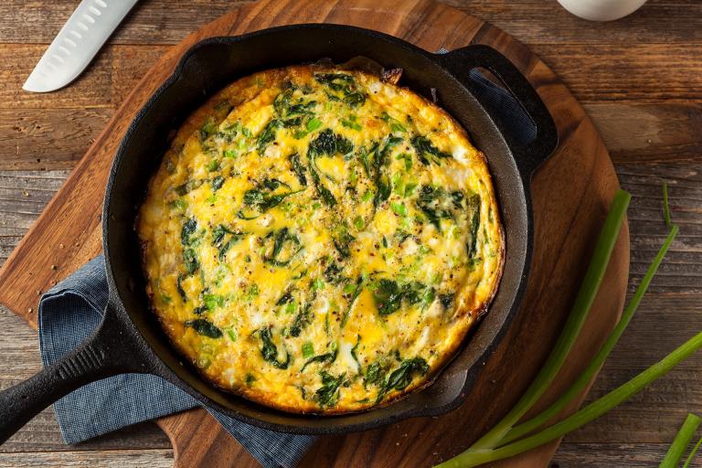 a spinach frittata in a pan with crumbled cheese